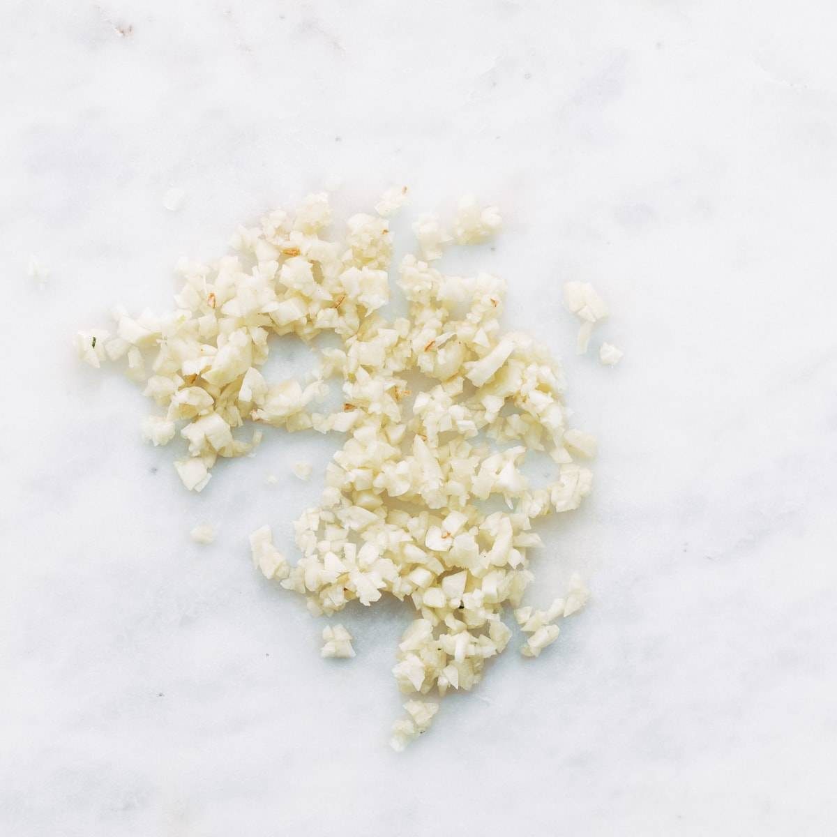 Pieces of minced garlic on a white surface.