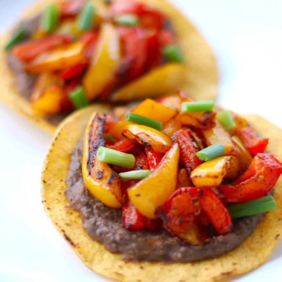 Two roasted bell pepper tostadas on tortillas. 