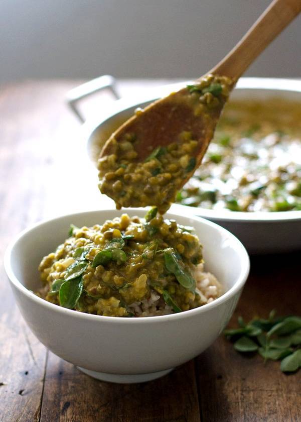 Monggo beans in a white bowl with a wooden spoon.