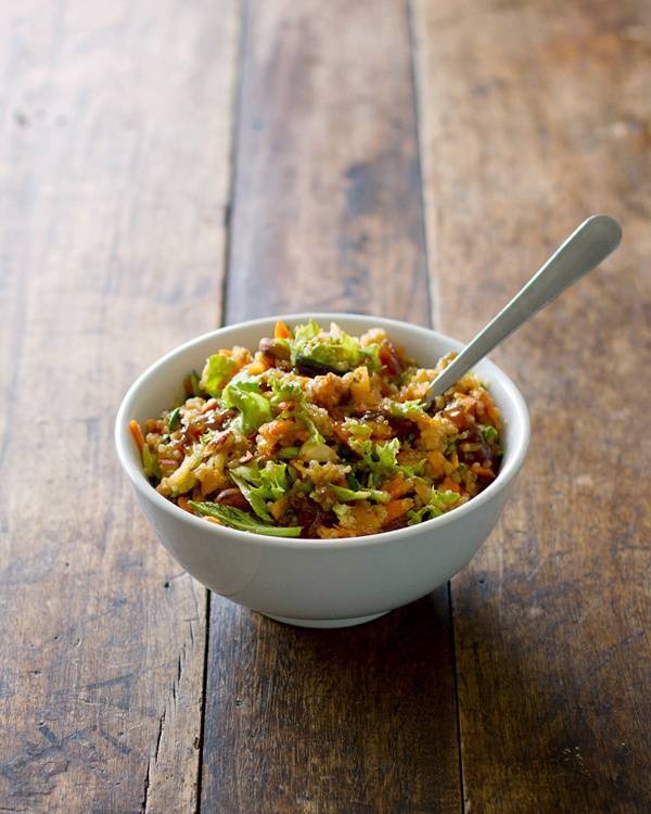 Apple quinoa salad in a white bowl with a spoon.