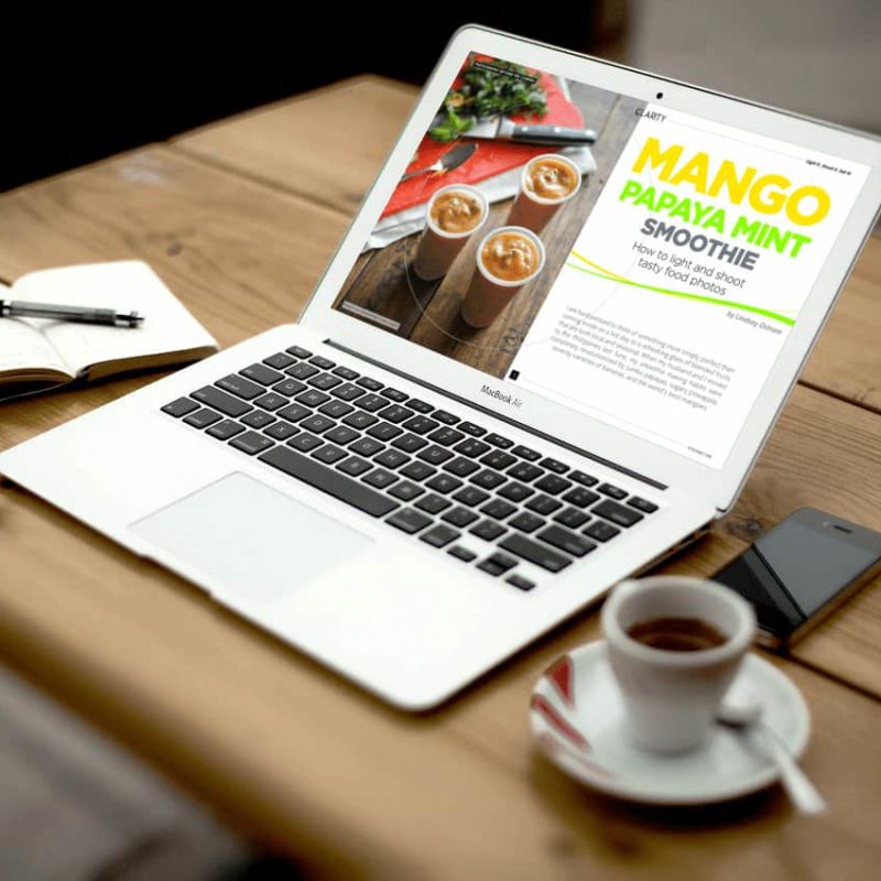 A laptop on a table with a cup of coffee.