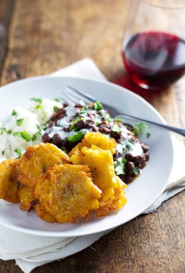 Garlic tostones on a white plate with rice and beans.