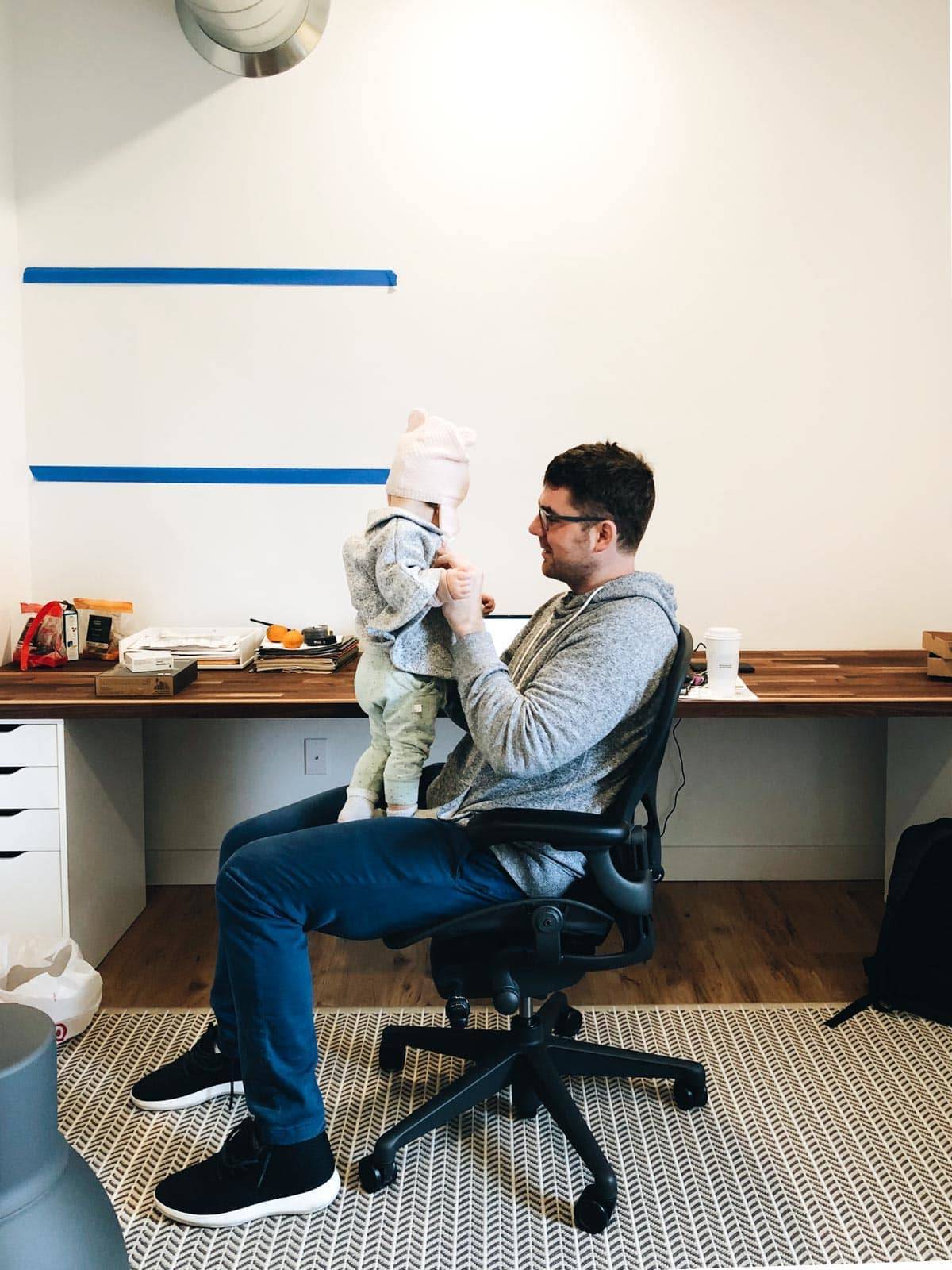A man sitting on a chair and playing with his child on his lap.