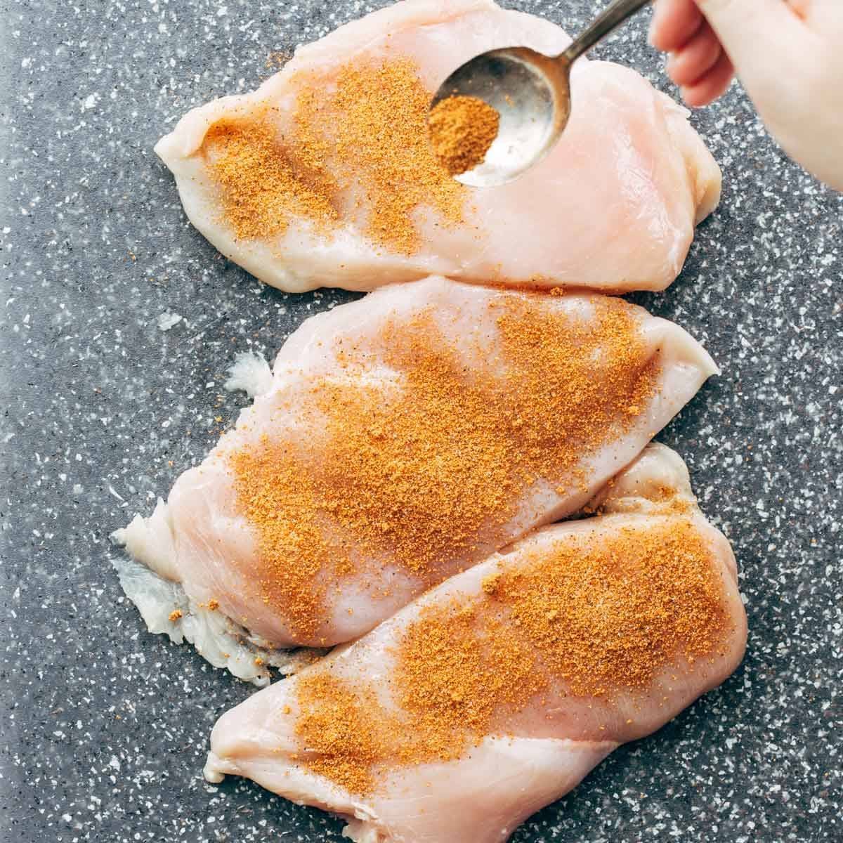Seasoning chicken breasts.
